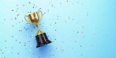 Colorful confetti falling over gold cup sitting over blue background