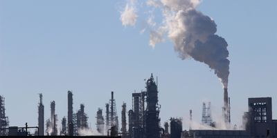 Image of oil refinery with smoke coming out into the sky