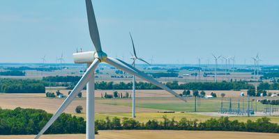 Image of Aerial close up of wind turbine with wind farm in background and substation