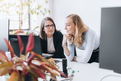 Two women work at a computer in an office