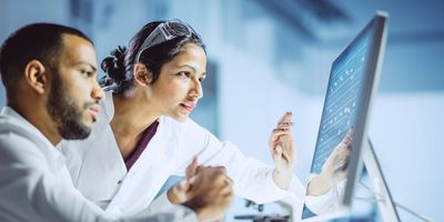 Two scientists work at a computer in the lab