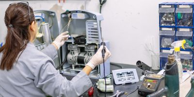 Woman works on a lab instrument with a soldering iron