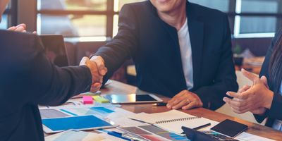 Businesspeople shake hands over a desk