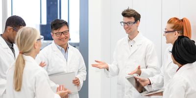 Six health professionals gather around talking in their workplace