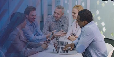 Group of coworkers sitting at a table talking and smiling