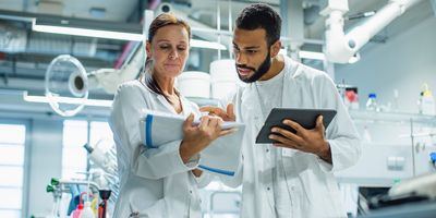 Two scientists, one male, one female, looking at paperwork in the lab