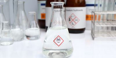 clear liquid in glass beaker with toxic symbol on it