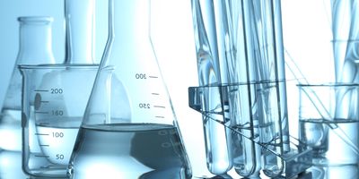 Various beakers and test tubes on top of a lab bench with clear liquids in them.