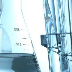 Various beakers and test tubes on top of a lab bench with clear liquids in them.