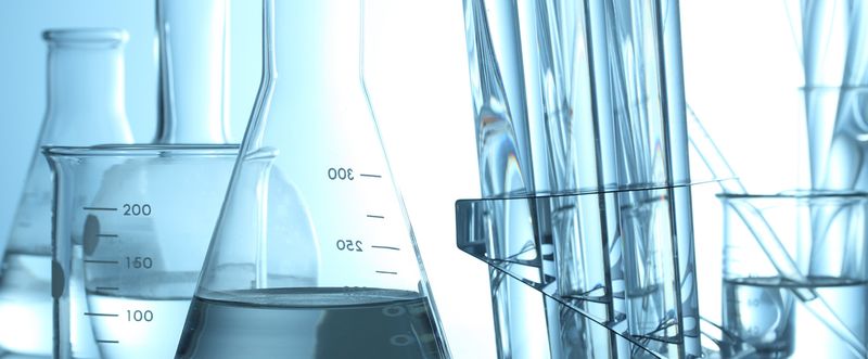 Various beakers and test tubes in lab with clear liquids in them