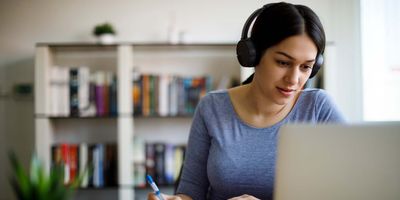 A woman working from home on a laptop with headphones on