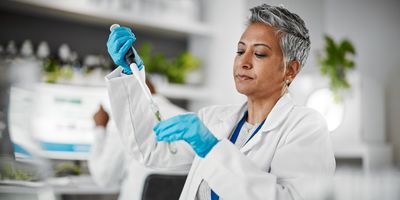 Woman pipettes into a test tube in a lab