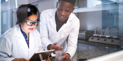 Two scientists discuss data on a tablet