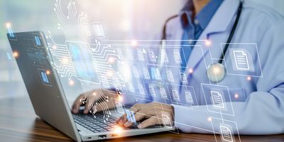 a doctor in a white lab coat with a stethescope around his neck uses an AI assistant to look at files on his laptop, shown as a faux hologram overlay