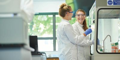 Two female scientists working at a fume hood