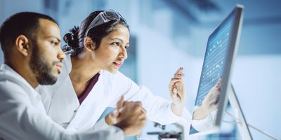 Two scientists discuss results on a lab computer