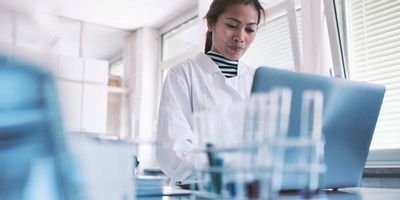 A female scientist stands over a computer and types on the keyboard in the lab