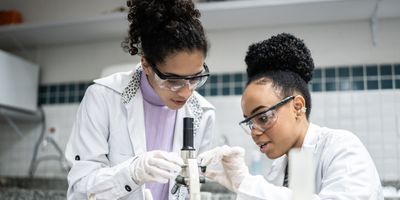 Black female teenage student learning to use a microscope