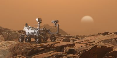 six-wheeled robot on a reddish brown rocky landscape meant to resemble mars with a pale white sun in the distance