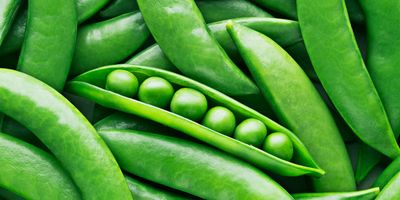 A pile of green pea pods with peas in them