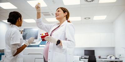 A pregnant researcher looking at samples in a test tube