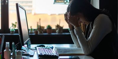 Women stressed out, head in heads, working at a computer