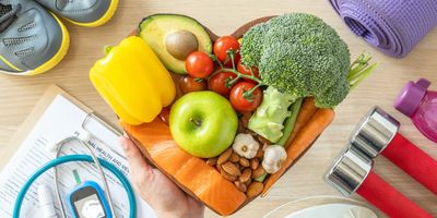 Heart shaped plate full of healthy food next to exercise shoes and a health chart