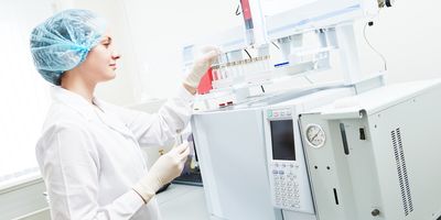 Female researcher putting flasks into gas chromatograph