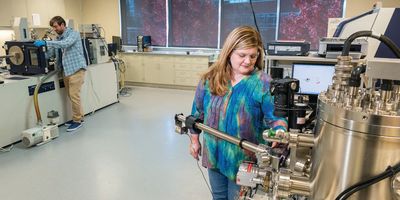 Scientists wearing regular clothes work on instrumentation in the the National Polymer Innovation Center.