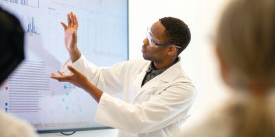 Male scientist explains a process with charts on a display