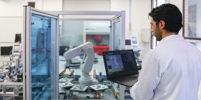 Male scientist programs a robotic arm in a laboratory