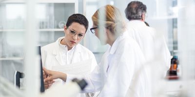 Two female scientists in a laboratory view a computer screen