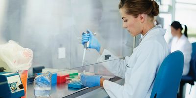 Female scientist uses a pipette under a fume hood