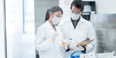 Couple of chemists working at the lab in a chemical plant and mixing products in test tubes