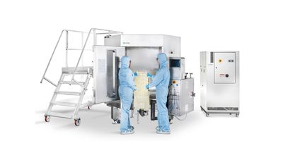 Two researchers in ppe loading the Xcellerex on a white background