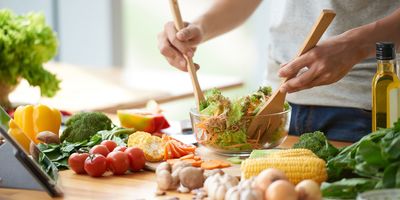 Man mixing vegetable salad in bowl