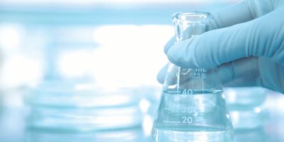 Gloved hand holds a flask in a lab