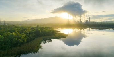 Landscape picture depicting a factory emitting carbon into the air near a forest