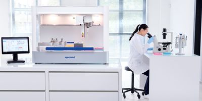 The new epMotion liquid handler in a lab next to a researcher looking in a microscope