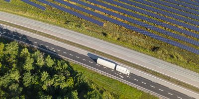 Transport truck driving down a road next to solar panels