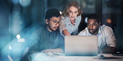 Three workers looking at a laptop discussing a project