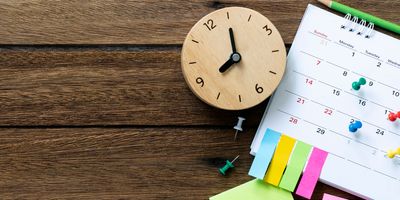 Wooden clock next to a calendar 