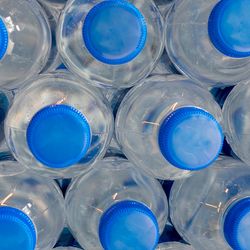 a close up photo of a stack of plastic water bottles with blue caps