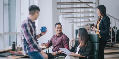 Coworkers cheerfully chatting and having coffee at work