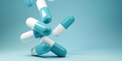 Blue and white pills falling onto a light blue table with light blue background