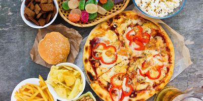 Junk food inclding pizza, fries, chips, laid out on a table