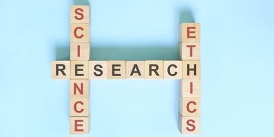 wooden letter cubes on a blue background spelling out "research" in black letters with the words "science" and "ethics" in red, intersecting like a crossword puzzle