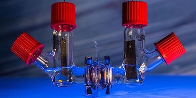 a prototype electronic sensor made of connecting clear tubes containing wiring with four red caps sits on a blue table