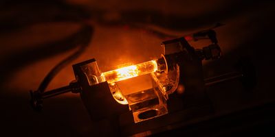 a glass-looking tube is held in a clamp and subject to flash Joule heating, generating an orange glow within the tube