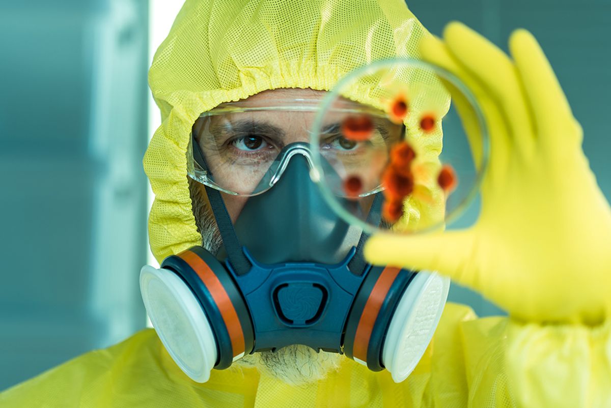 Scientist in PPE holds up a petri dish holding cultured cels